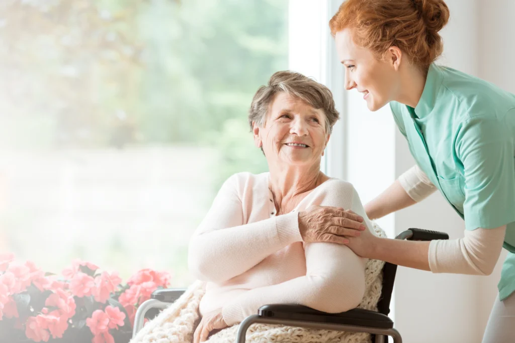 Ambulante Pflege - eine Pflegerin unterhält sich mit einer Seniorin im Rollstuhl